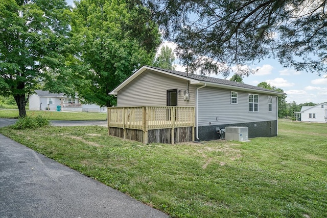 view of side of property featuring central air condition unit, a wooden deck, and a yard