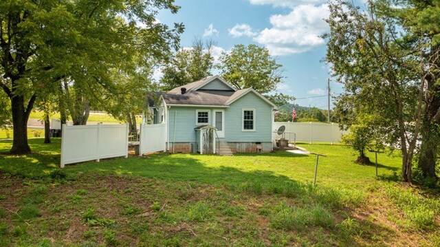 back of house featuring a yard, crawl space, and fence