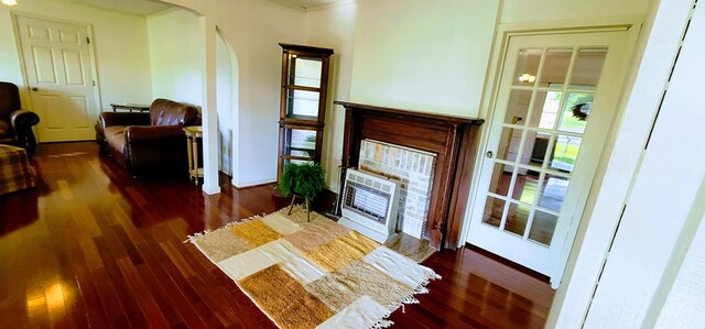 living area with heating unit, arched walkways, and dark wood-type flooring