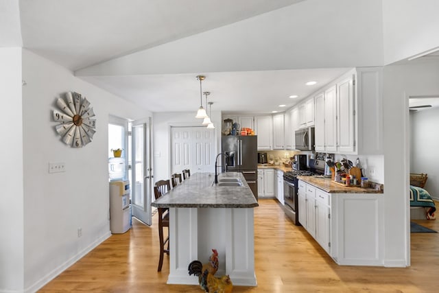 kitchen featuring a center island with sink, appliances with stainless steel finishes, a breakfast bar area, white cabinetry, and pendant lighting