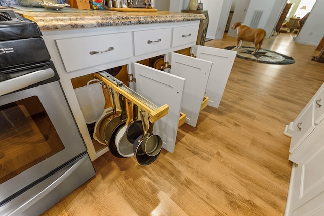 interior details with light countertops, white cabinets, light wood-style flooring, and stainless steel electric range