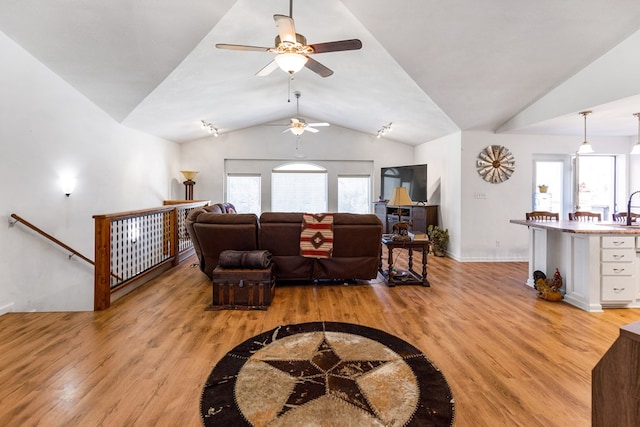 living room with vaulted ceiling, light wood-style flooring, and baseboards