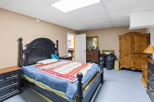 bedroom featuring concrete flooring and a paneled ceiling