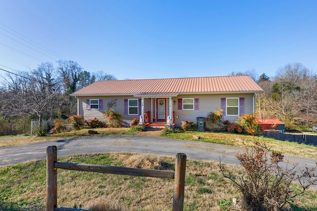 ranch-style house with metal roof, fence, and driveway