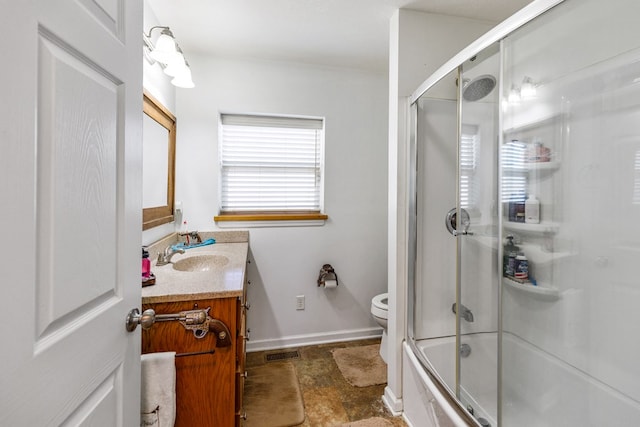 bathroom featuring visible vents, toilet, combined bath / shower with glass door, vanity, and baseboards