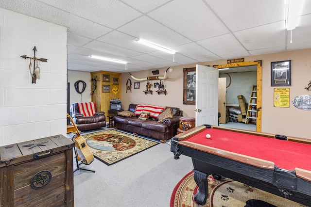 playroom featuring a paneled ceiling and concrete block wall