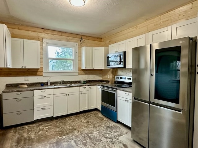 kitchen with a sink, stainless steel appliances, dark countertops, and white cabinets