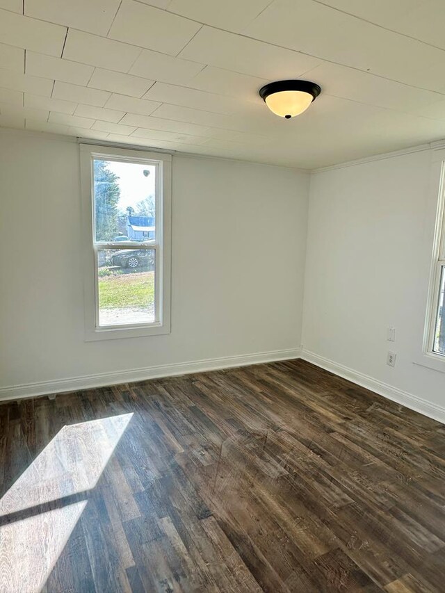 spare room featuring dark wood-style floors and baseboards