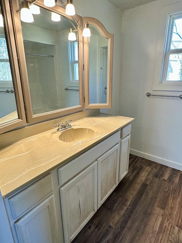 full bathroom with vanity, wood finished floors, and baseboards