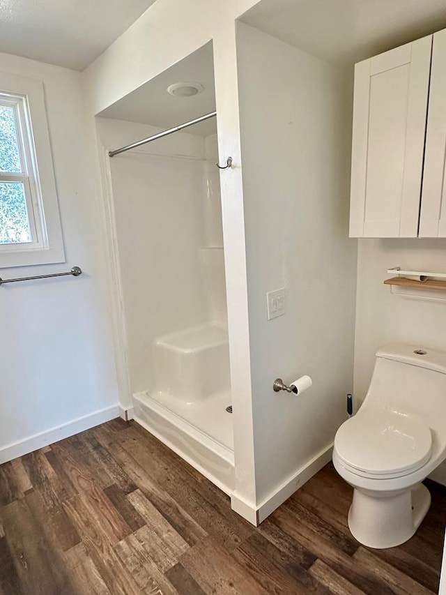 full bathroom with a shower stall, toilet, baseboards, and wood finished floors