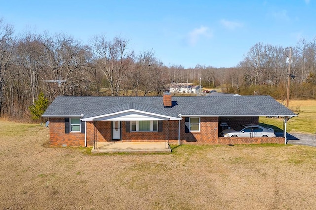 view of front of home featuring a chimney, a front yard, an attached carport, brick siding, and a patio area