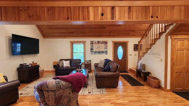 living room featuring lofted ceiling, light wood finished floors, baseboards, wood ceiling, and stairs