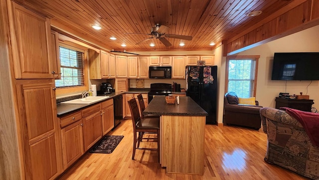 kitchen with a sink, plenty of natural light, dark countertops, and black appliances