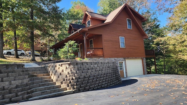 view of side of property featuring stone siding, driveway, and a garage