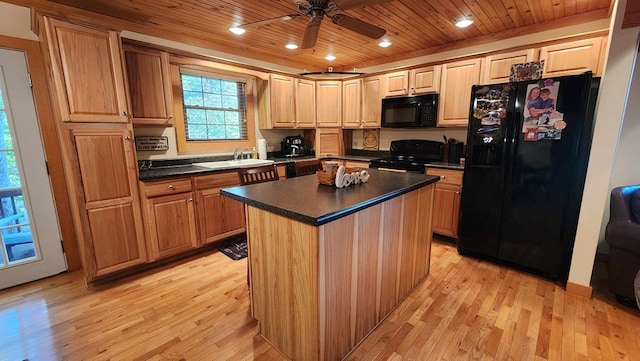 kitchen featuring light wood finished floors, dark countertops, wood ceiling, black appliances, and a sink