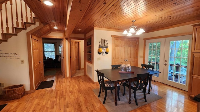 dining space with light wood-type flooring, a notable chandelier, wooden ceiling, and french doors