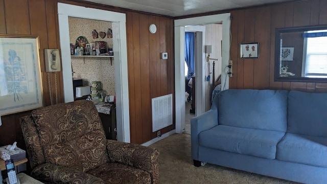 living room with carpet flooring, visible vents, and wooden walls