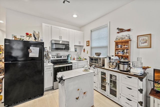 kitchen with stainless steel appliances, white cabinets, light countertops, a center island, and glass insert cabinets