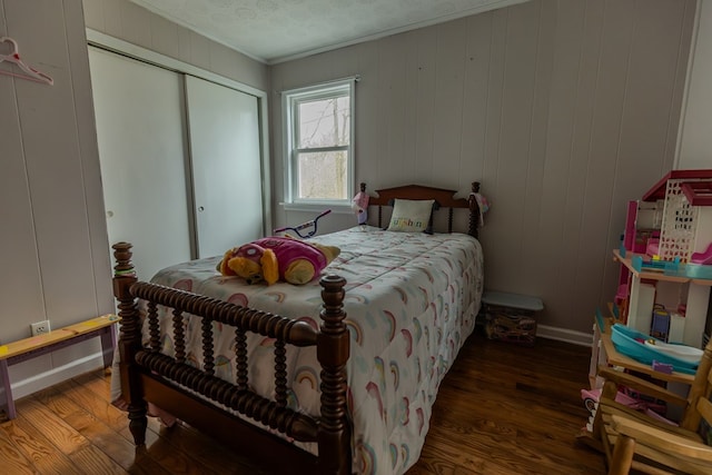 bedroom with a textured ceiling, a closet, dark wood finished floors, and crown molding