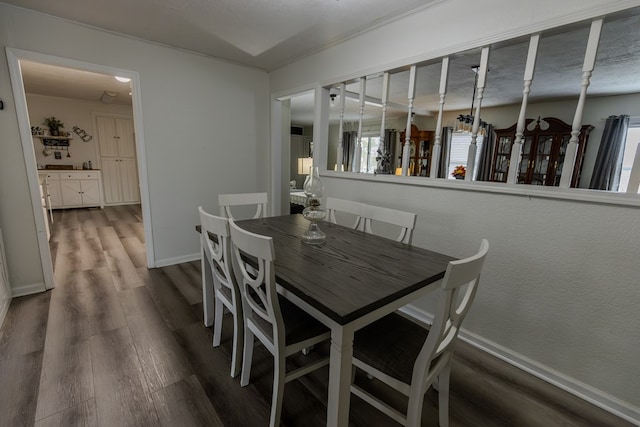 dining space with baseboards, wood finished floors, and a textured wall