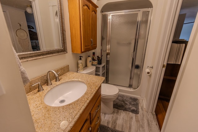 bathroom with toilet, a stall shower, wood finished floors, and vanity