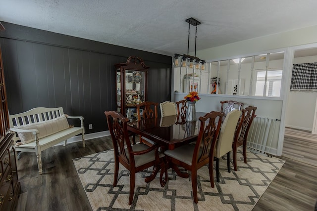 dining area featuring a textured ceiling, baseboards, and wood finished floors