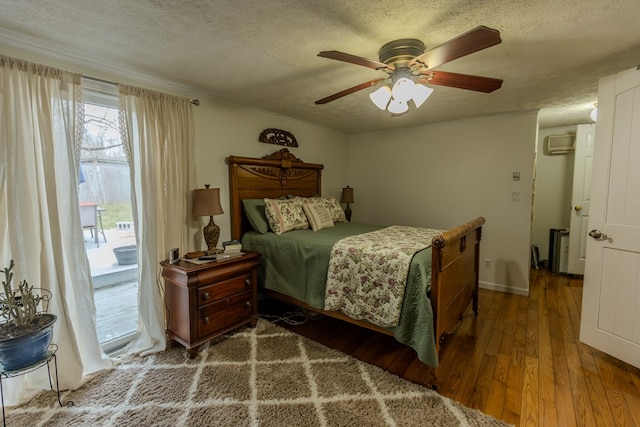 bedroom featuring a ceiling fan, ornamental molding, wood finished floors, a textured ceiling, and an AC wall unit