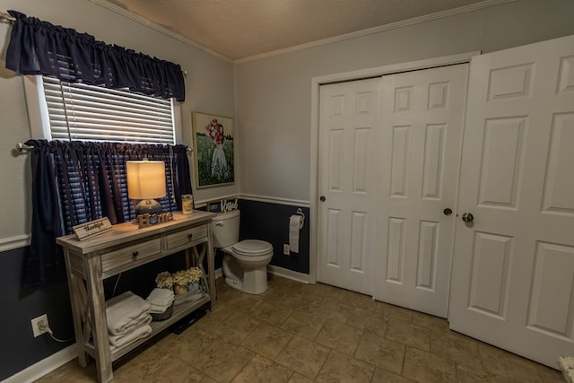 bathroom featuring baseboards, toilet, stone finish floor, a textured ceiling, and crown molding