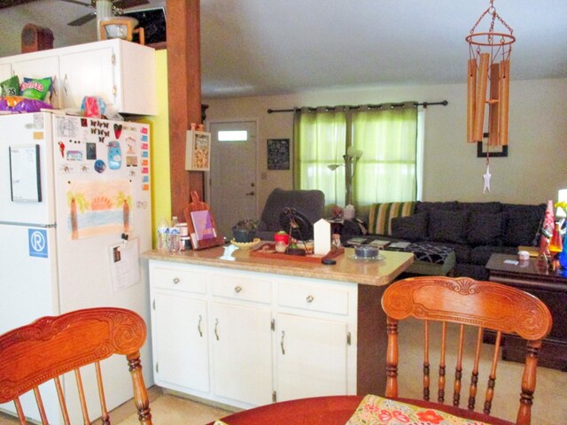 kitchen featuring white cabinets, open floor plan, freestanding refrigerator, hanging light fixtures, and light countertops