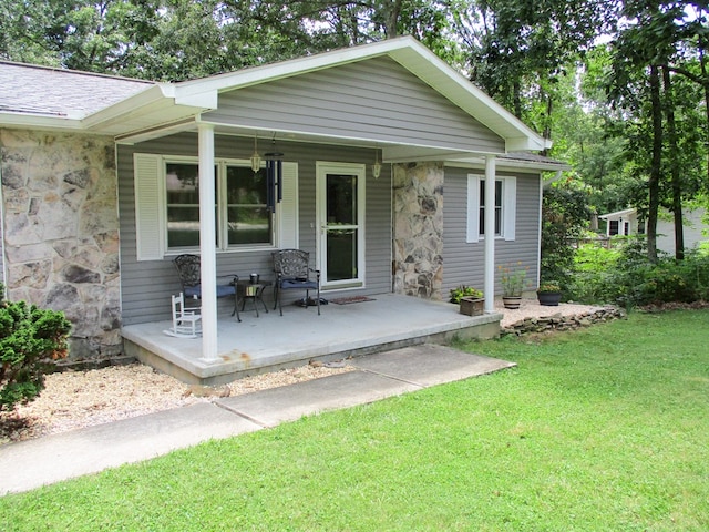 exterior space with stone siding, a yard, roof with shingles, and a porch