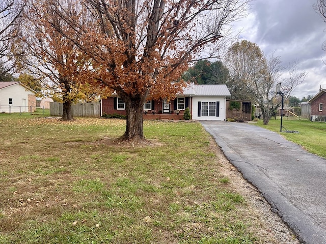 ranch-style house with aphalt driveway, brick siding, fence, and a front lawn