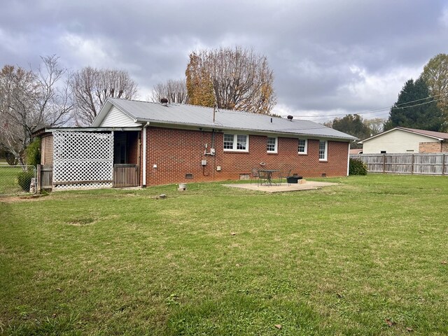 rear view of house with a lawn, a patio, crawl space, fence, and brick siding