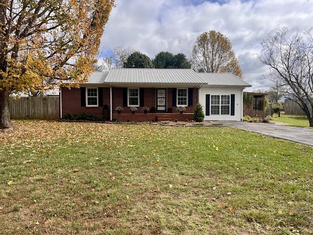 single story home featuring metal roof, fence, a front lawn, and brick siding