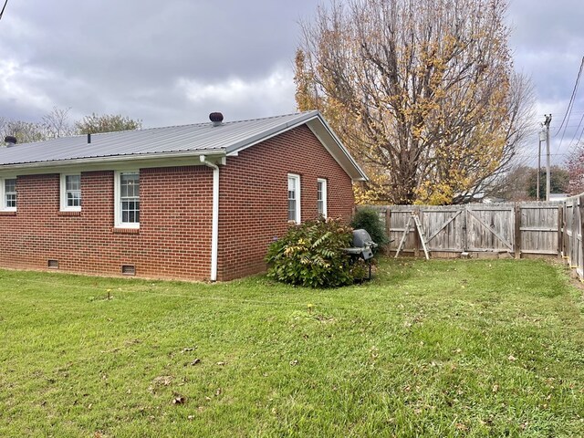 view of property exterior featuring a fenced backyard, crawl space, a gate, a yard, and brick siding