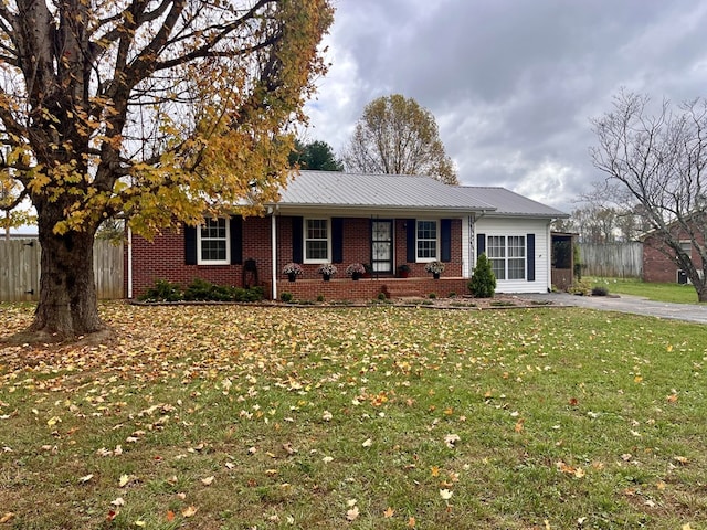 ranch-style house featuring brick siding, a porch, a front yard, metal roof, and fence