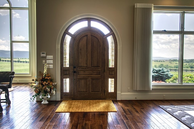 entryway featuring dark wood-type flooring, arched walkways, and baseboards