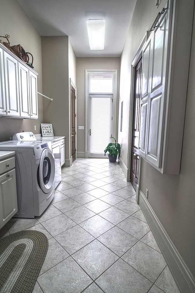 laundry room with separate washer and dryer, light tile patterned flooring, cabinet space, and baseboards