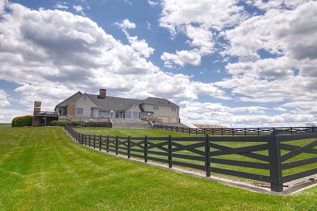 exterior space featuring a rural view, a lawn, and fence