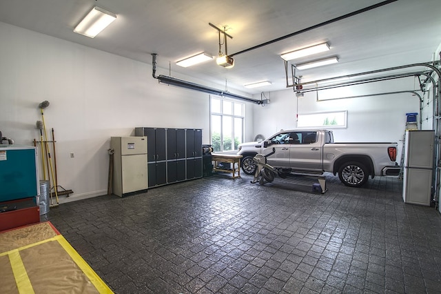 garage featuring baseboards, freestanding refrigerator, and a garage door opener