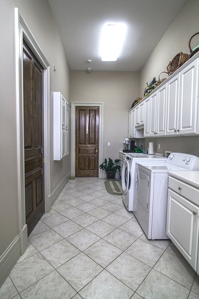 laundry room with light tile patterned floors, independent washer and dryer, cabinet space, and baseboards