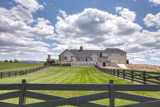 view of yard featuring a garage, driveway, a rural view, and fence