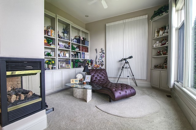 interior space featuring carpet, built in shelves, ceiling fan, and a multi sided fireplace