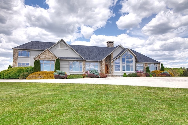 view of front of home with a front yard, a chimney, and stucco siding