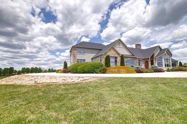 view of front of home featuring stone siding, a chimney, and a front lawn