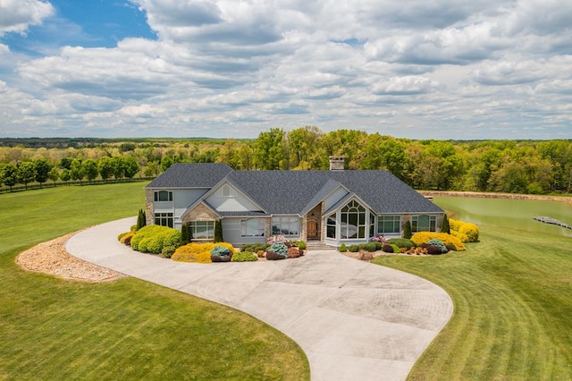 view of front of property with curved driveway, a front lawn, and a wooded view