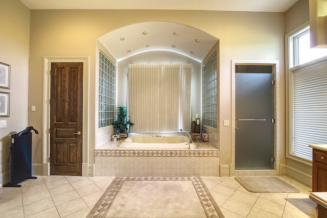 bathroom featuring baseboards, a jetted tub, a shower stall, and tile patterned floors