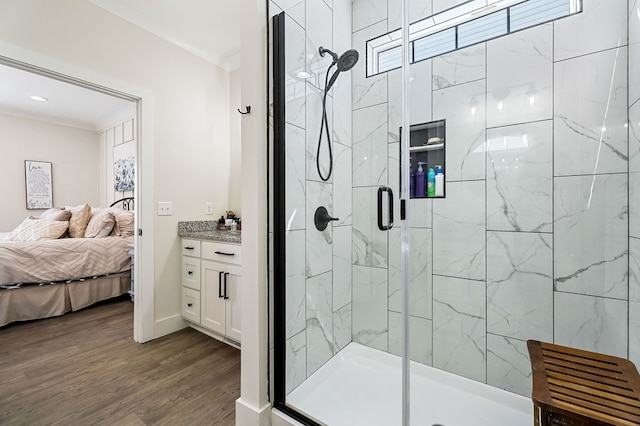 ensuite bathroom featuring connected bathroom, a shower stall, baseboards, and wood finished floors