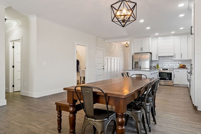 dining room featuring wood finished floors, baseboards, recessed lighting, crown molding, and a notable chandelier