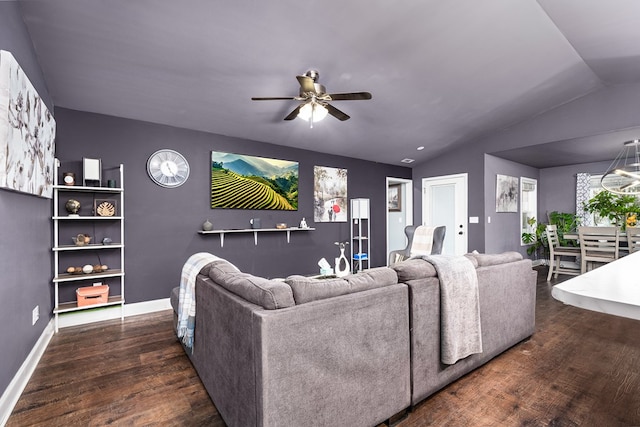 living room featuring vaulted ceiling, ceiling fan with notable chandelier, wood finished floors, and baseboards