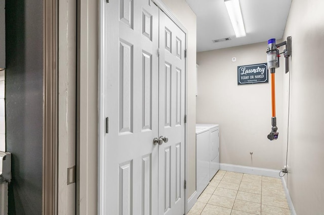 washroom featuring laundry area, washer and clothes dryer, light tile patterned flooring, and baseboards